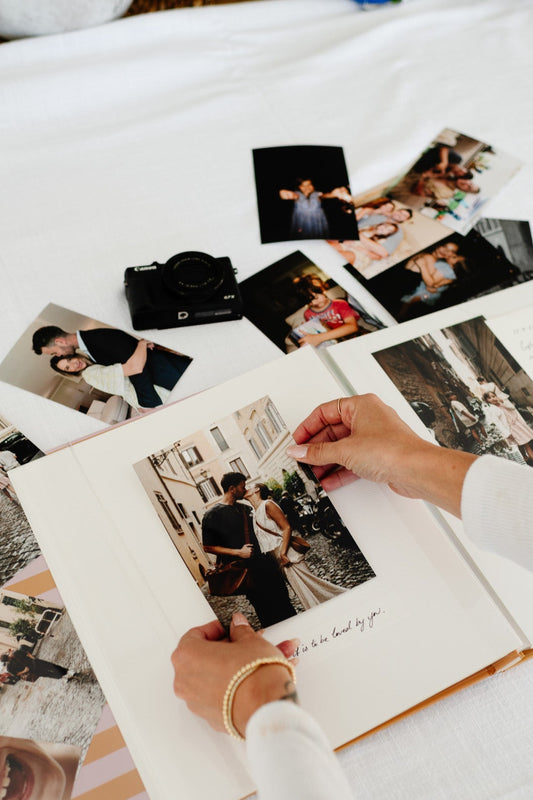 Person arranging photos on a scrapbook with a focus on memories.